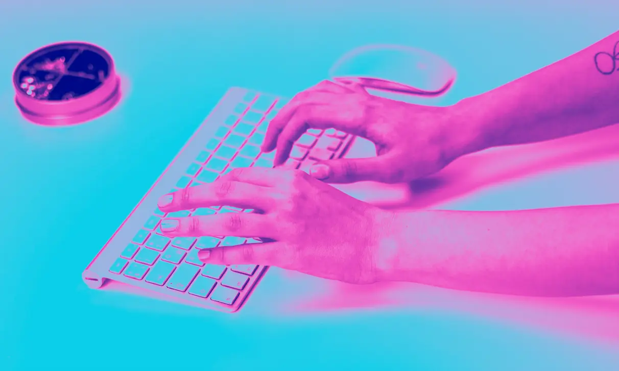Mãos digitando em um teclado, em duotom magenta e ciano